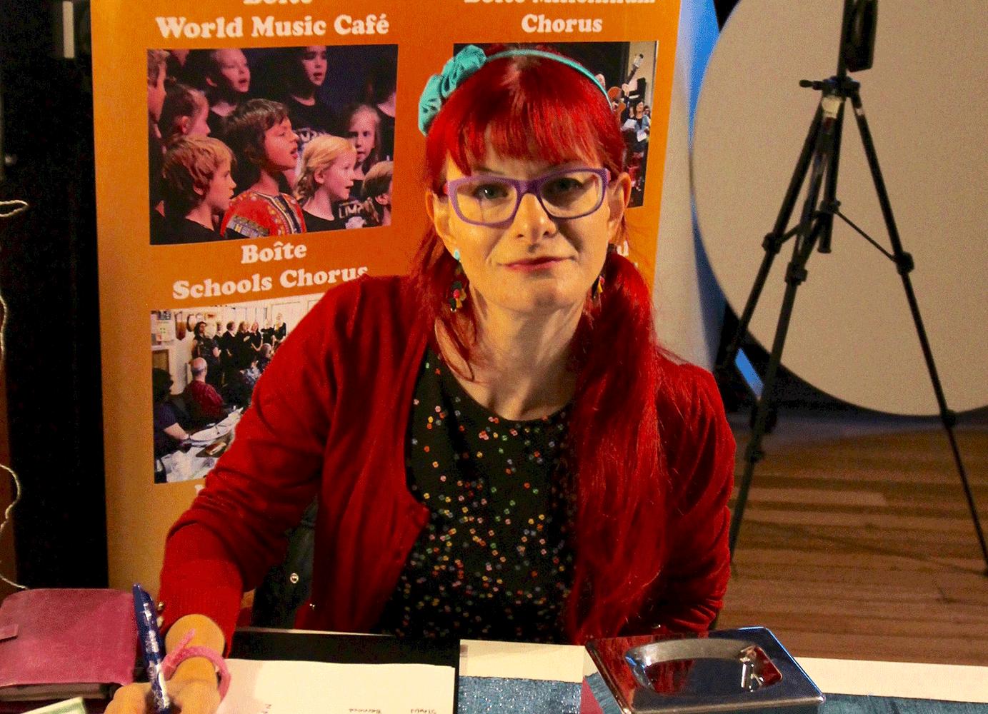 A woman with bright red hair and glasses sitting at a desk