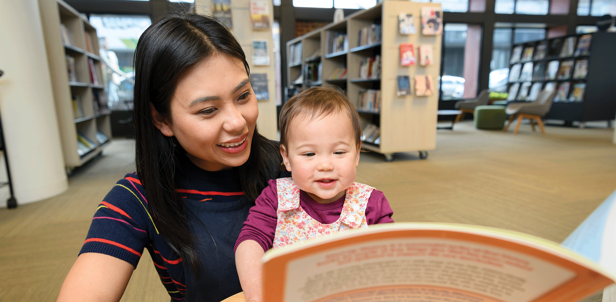 A woman reading to her daughter in a library