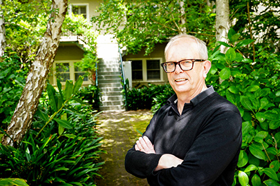 Man with glasses in black shirt standing at path to front garden