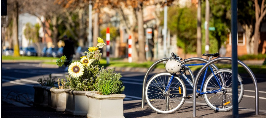 A bike and a planter box on a sunny street.