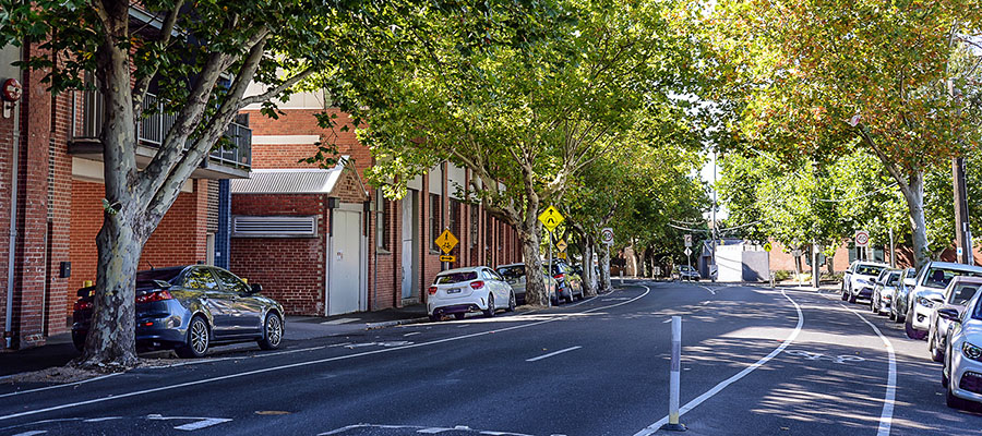 Leafy street with brick buildings down one side