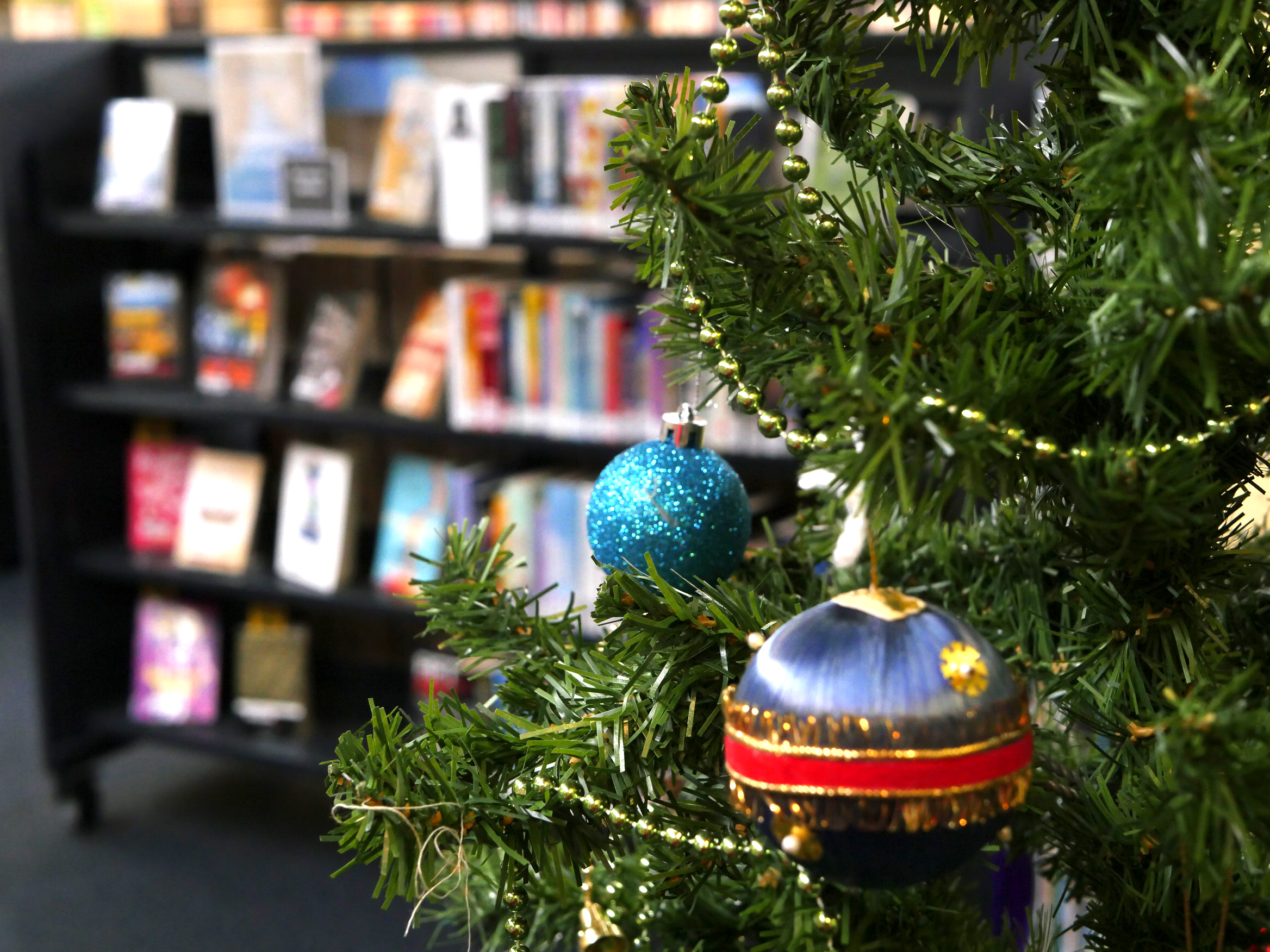 A Christmas tree in front of library shelving. 