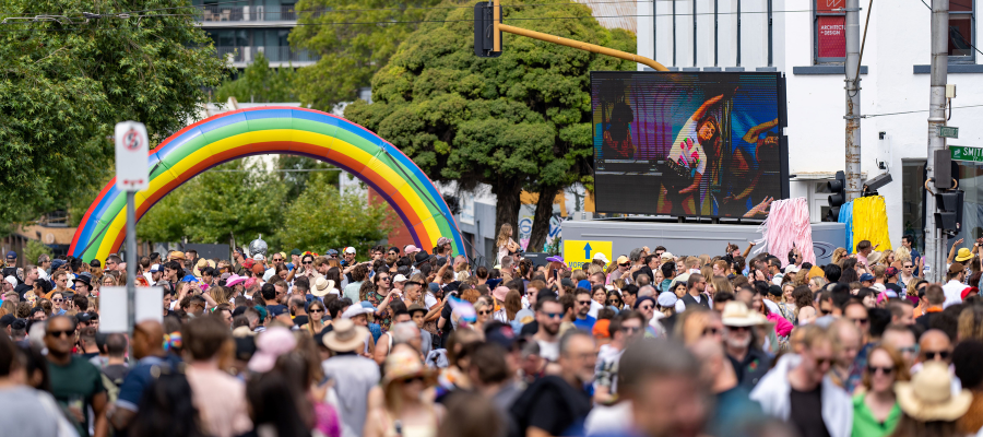 Photo of Yarra's pride festival, showing a crowd of people milling around in front of an inflated rainbow